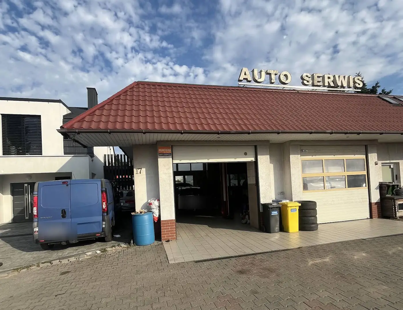 Budynek warsztatu z szyldem AUTO SERWIS i otwartą bramą